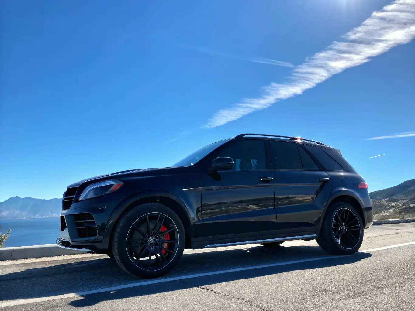 A modern SUV with premium carbon window tint, parked in front of a commercial building, highlighting its enhanced clarity and heat rejection properties.